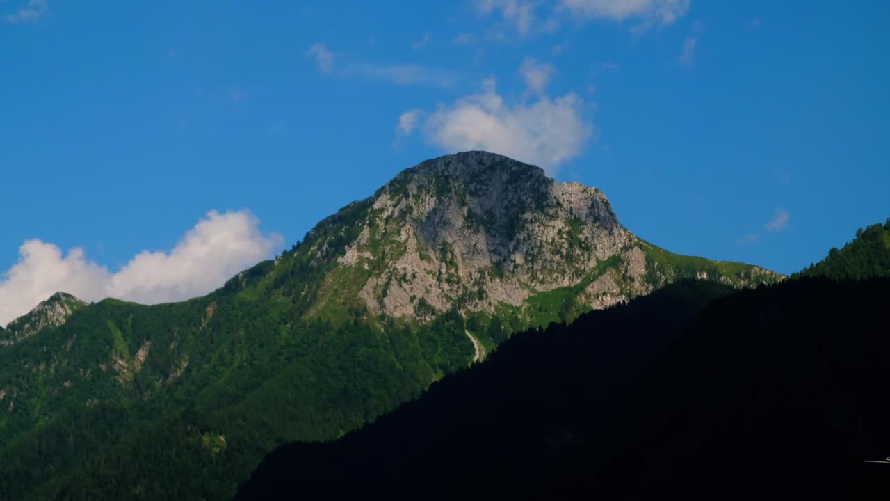 Timelapse aereo spettacolare di nuvole che si muovono velocemente sopra una vetta rocciosa in Val di Scalve, nelle Alpi Orobie. Maestoso paesaggio alpino italiano con cielo dinamico