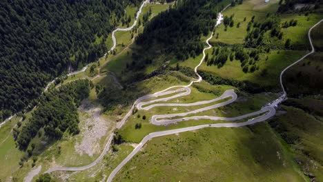 Imágenes-Aéreas-De-Arriba-Hacia-Abajo-De-Un-Camino-Sinuoso-En-Los-Alpes-Austriacos,-Mientras-Las-Motocicletas-Y-Los-Automóviles-Pasan-Por-Las-Curvas