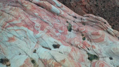 view from a drone of a massive rock formation with a red-orange marble texture in the mountains during the day