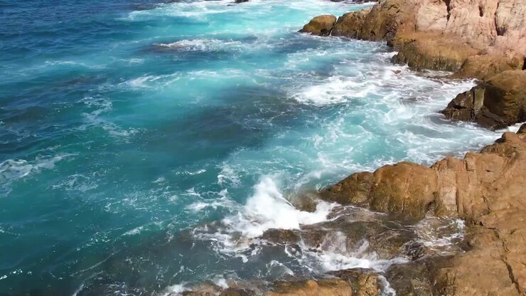 Beach paradise Cabo Mexico ocean beach pans up from rocks to reveal ships on the horizon