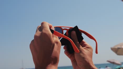 cleaning sunglasses on the beach