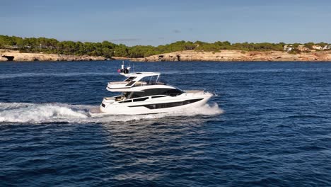slow motion drone shot of luxury yacht driving next to beautiful mediterranean coastline