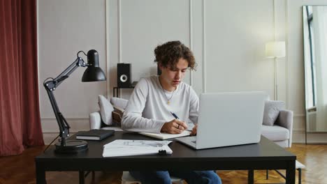 young man studying and drawing at home