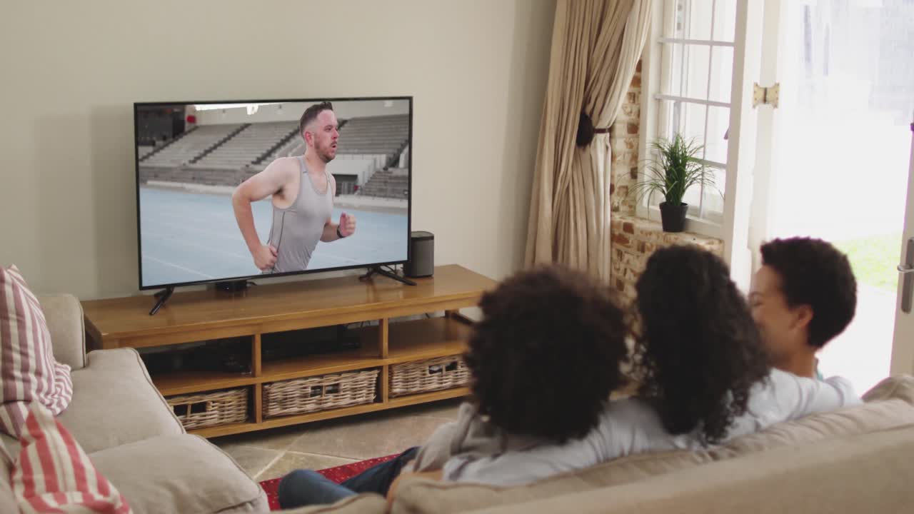 Composizione di famiglia felice seduta insieme a casa che guarda un evento di atletica leggera di corsa in TV.