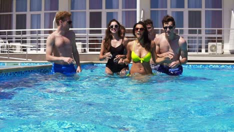 felices jóvenes amigos alegres bailando y divirtiéndose en la piscina refrescándose en el agua en un caluroso día de verano