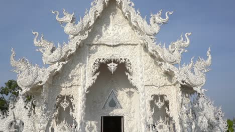 tilt revelation of the white temple main entrance to the prayer house at chiang rai, thailand.