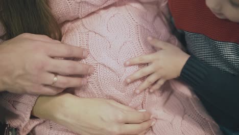 Große-Und-Kleine-Hände-Auf-Dem-Bauch-Einer-Schwangeren-Frau-Im-Pullover