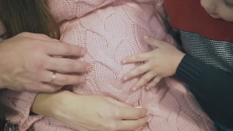 big and small hands on pregnant woman belly in pullover