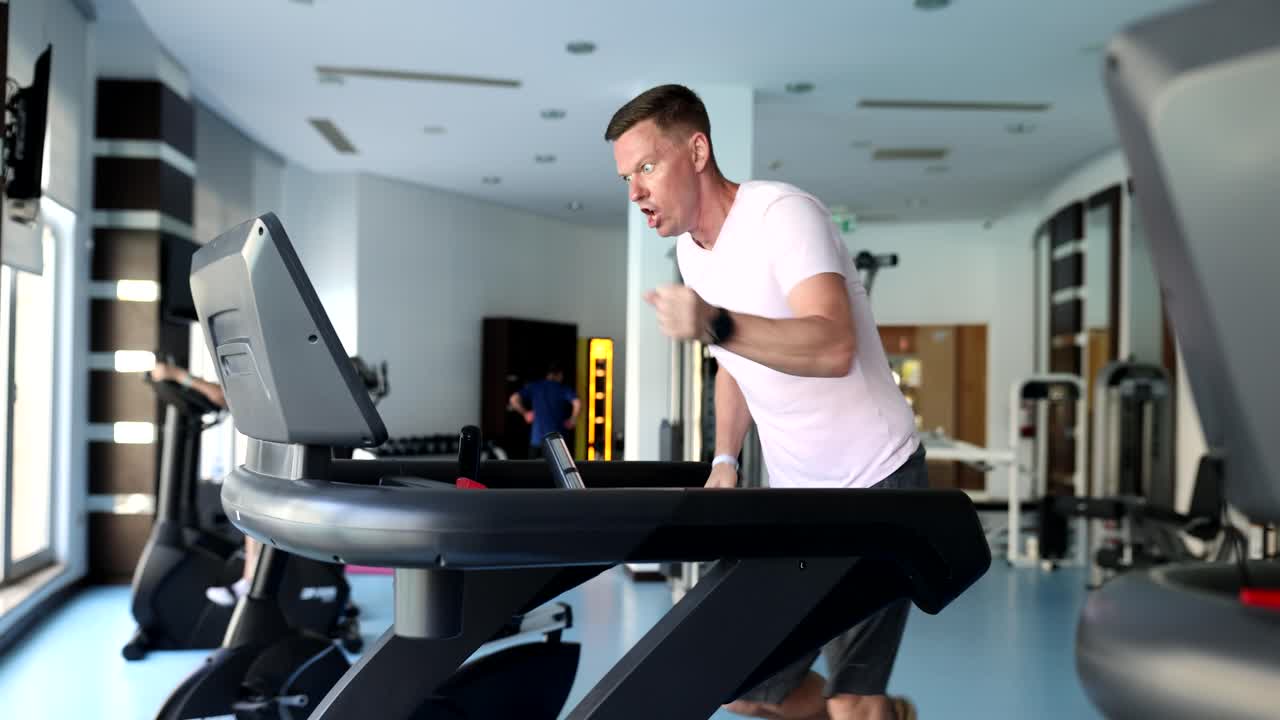 Terli, yorgun genç sporcu spor salonunda koşu bandında koşuyor.