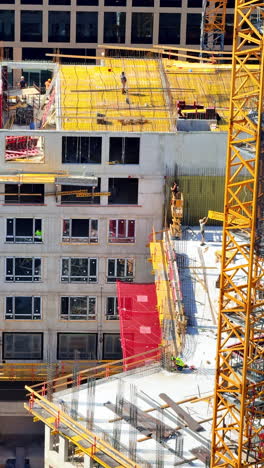 daytime urban construction site. workers are actively constructing a multi-story building in a busy city, surrounded by cranes and scaffolding