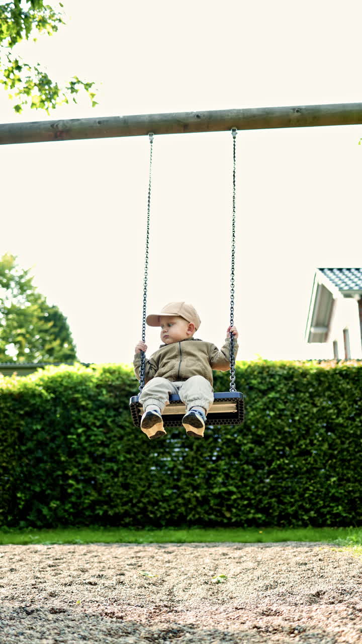 Bambino carino che si dondola sull'altalena in un parco giochi. Un bambino piccolo che si dondola e ride. Un bambino che gioca e si diverte in un parco giochi nel parco.