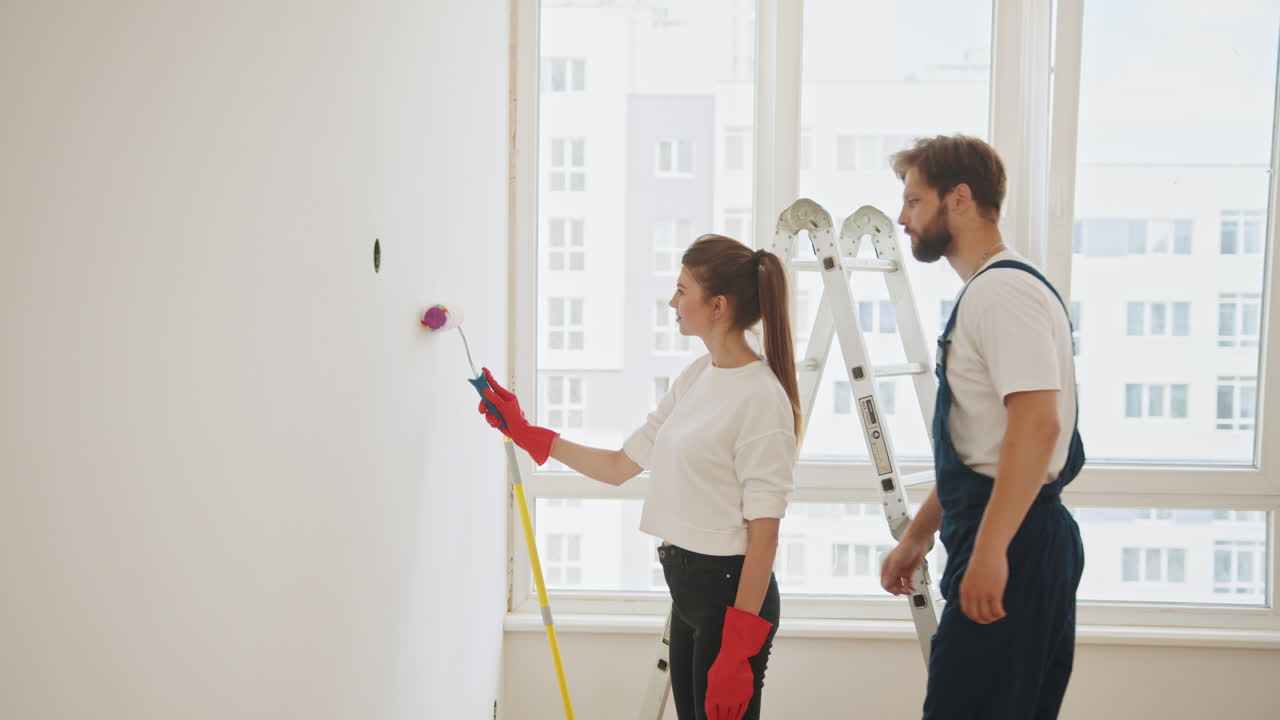 una pareja pintando una pared en su casa.