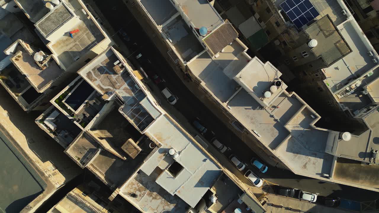 Bird’s eye top down view of dense Maltese rooftops, narrow streets, and historic stone urban patterns, textured backdrop with cars driving