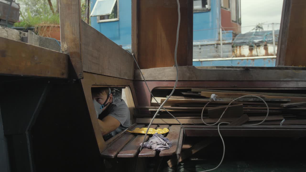 갑판 내부 나무 보트 선실 밑면에 마스크 페인팅을 하고 있는 청년