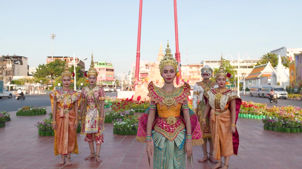 Bailarines tailandeses con elaborados trajes clásicos actúan al aire libre en el Columpio Gigante bajo la luz brillante del día.