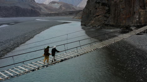 hunza, gilgit-baltistan, pakistan의 hunza 강 위의 hussaini 현수교를 건너는 파키스탄 여성