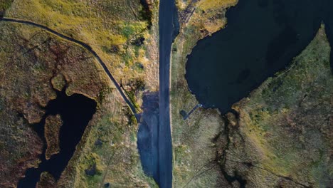 carretera de montaña abandonada con lagos en las islas feroe en un día soleado y ventoso