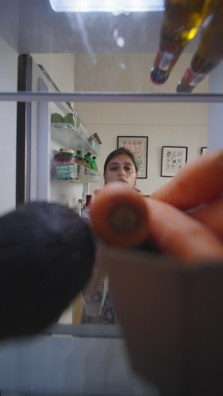 женщина смотрит внутрь холодильника