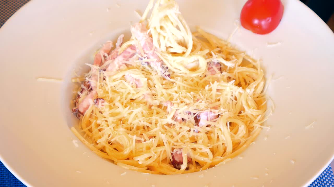 comiendo de cerca pasta italiana carbonara con parmesán y tocino.