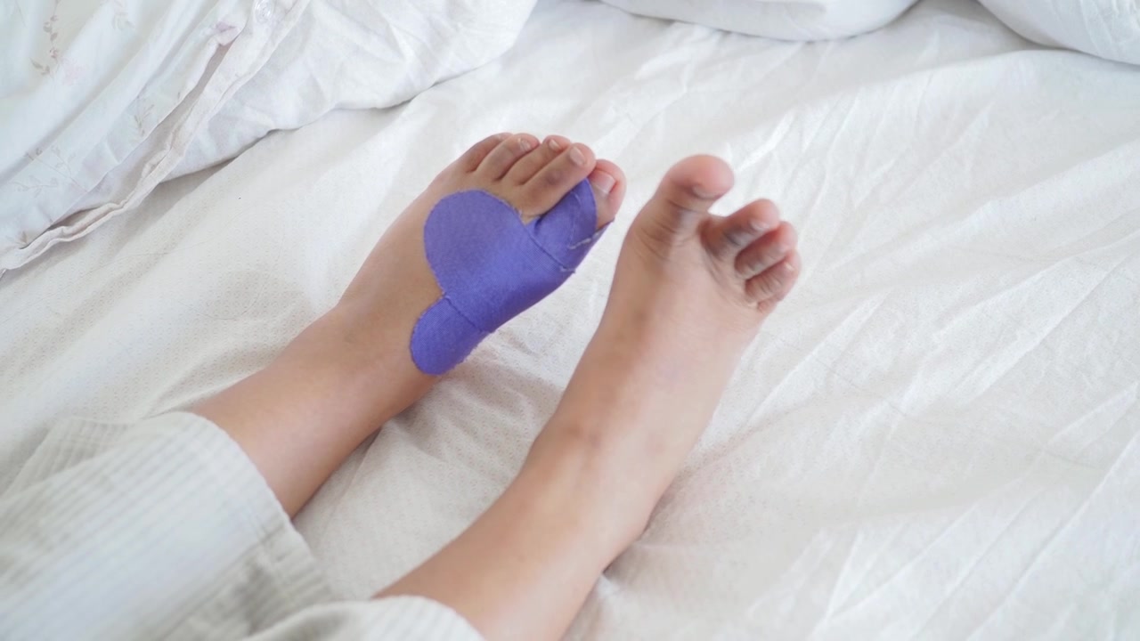 Piedi di una persona con nastro kinesiologico viola a forma di cuore che muovono le dita