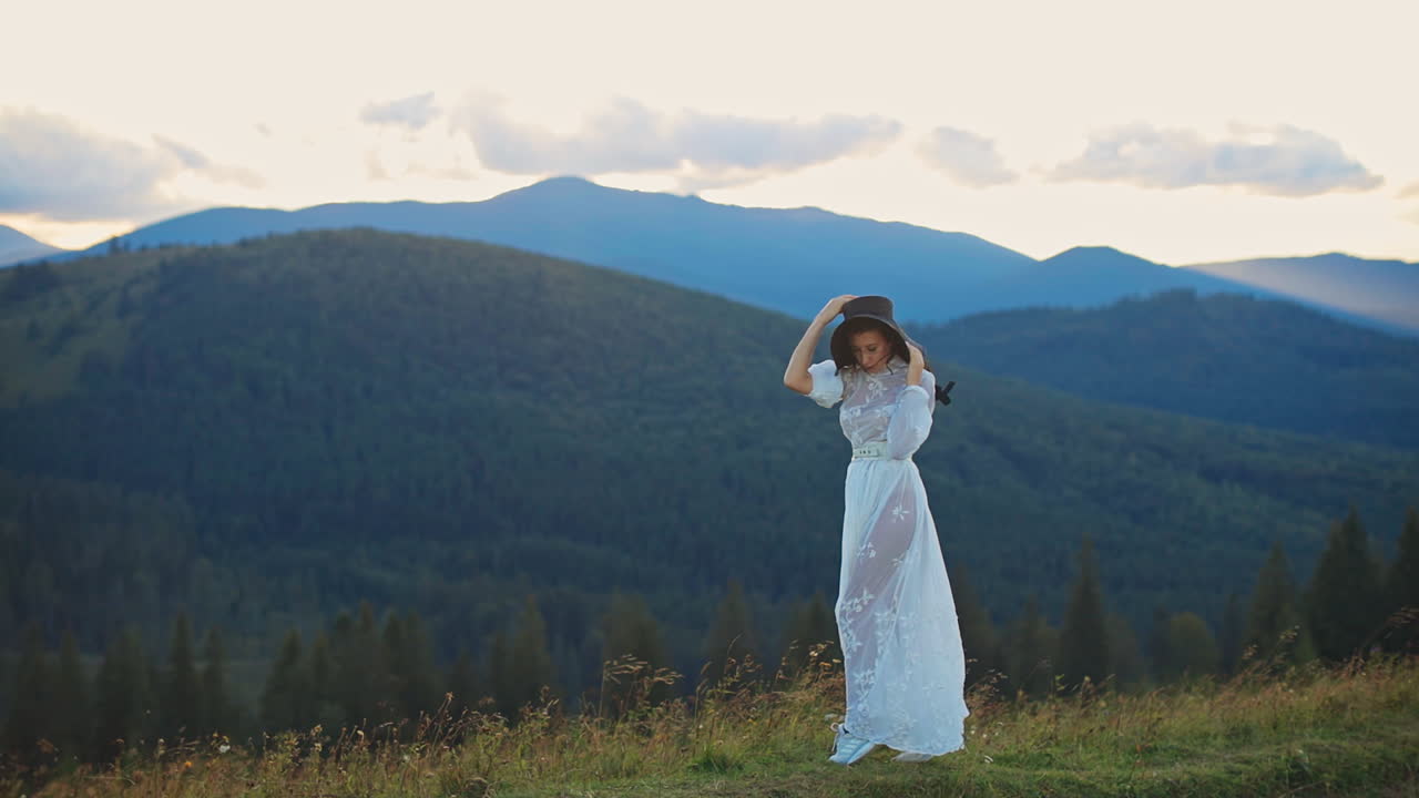 Woman in a White Dress in Mountains at Sunset