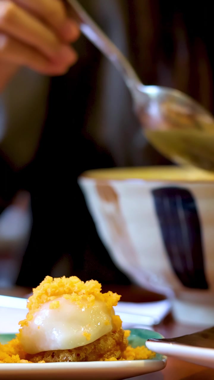 Close-up shot of a woman using a spoon to eat noodles from a ceramic bowl