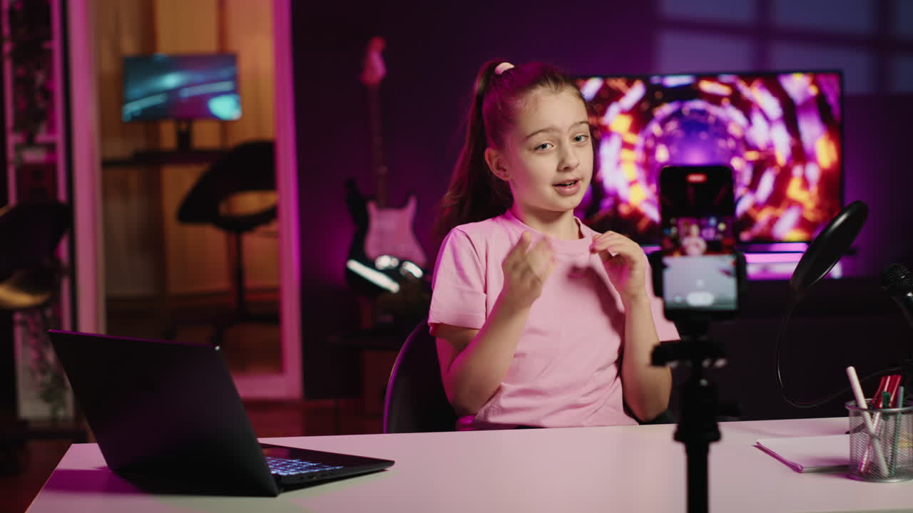 Pequena menina gravando a reação a vídeos da internet para canais de redes sociais.