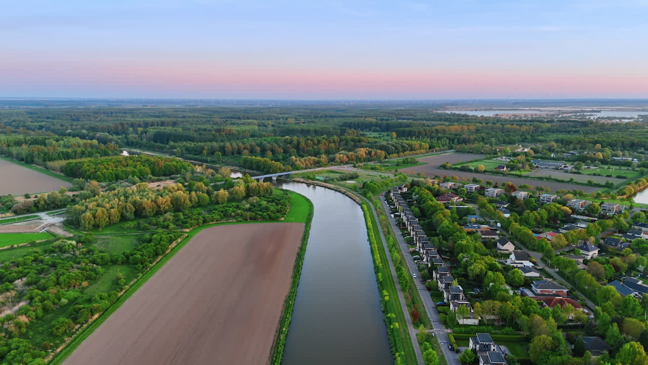 Footage over the canal in the picturesque landscape. Beautiful nature, village and agricultural field around the canal. Top view.