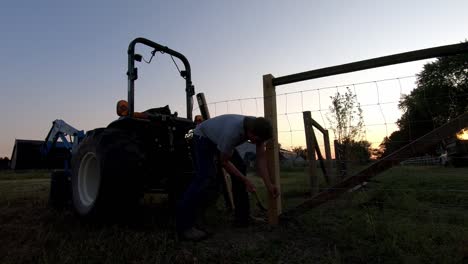 man fixing a fence in a rural farm, flat rock, michigan, usa - medium shot