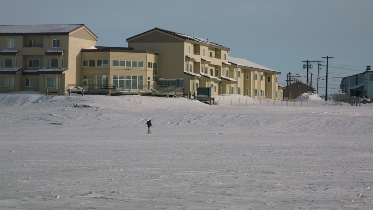 hombre caminando a través del lago congelado junto a la vivienda en utqiagvik barrow ladera norte de alaska en el ártico
