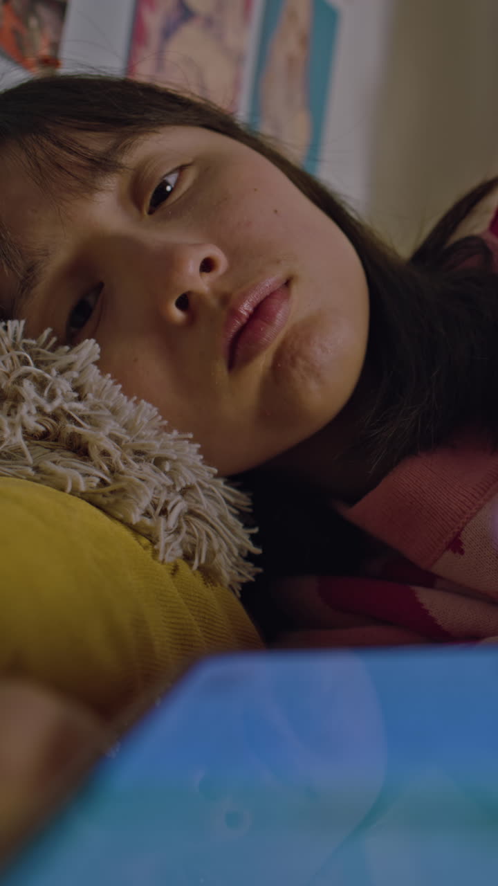 Teenage girl relaxing in her bedroom using a smartphone