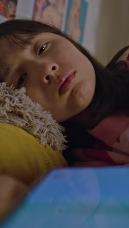 teenage girl relaxing in her bedroom using a smartphone