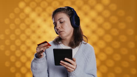 person with tablet in hands buying digital novel with credit card, hearing songs