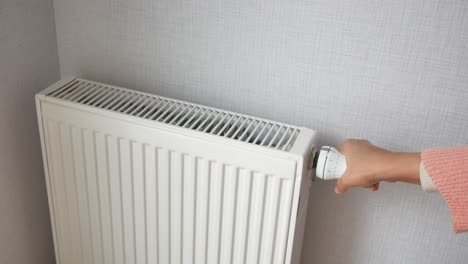 ajustando el termostato en un radiador blanco