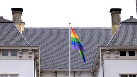 rainbow colors of lgbtq+ flag on top of historic city hall in zutphen, the netherlands, waving gently from the dutch historic facade in support of community