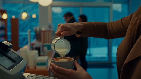 barista pouring milk to make latte art in a cafe
