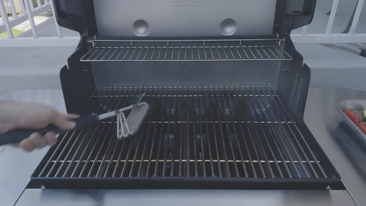 Straight-on shot of stainless steel bbq grates being cleaned by a stainless steel bristle free bbq brush