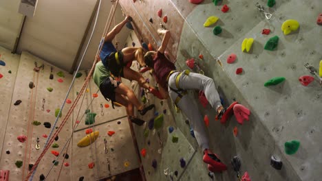 men and woman climbing an artificial wall at bouldering gym 4k