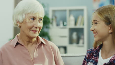 retrato de la linda y linda adolescente y su guapa y canosa abuela mirándose, sonriendo y abrazándose