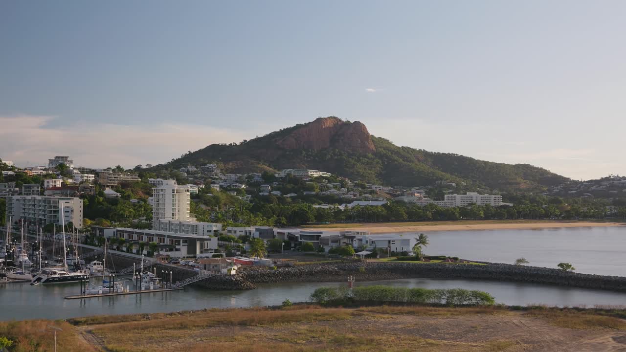 Looking through glass panels from a hotel room, overlooking the harbour and marina of Townsville Port and Castle Hill at dawn