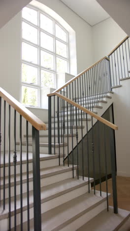 vertical video: modern staircase with wooden handrails and large window in bright home