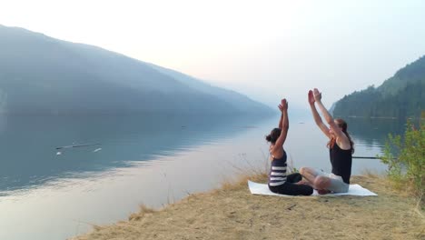 friends performing yoga near lakeside 4k