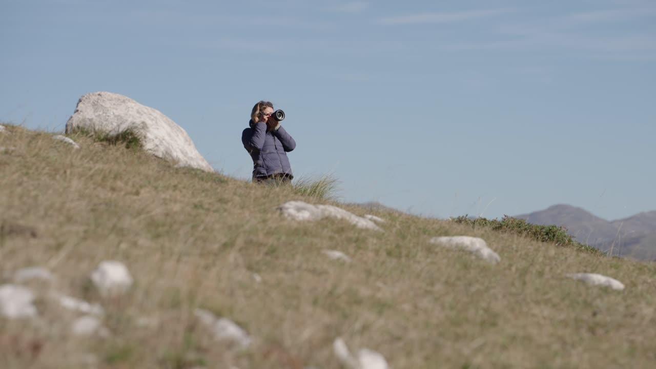 Donna in piedi sulla collina, che fotografa il panorama nel Parco Nazionale del Durmitor in Montenegro. - campo lungo