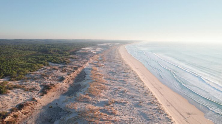 Ein menschenleerer goldener Sandstrand mit Meereswellen, die über das warme Ufer rollen