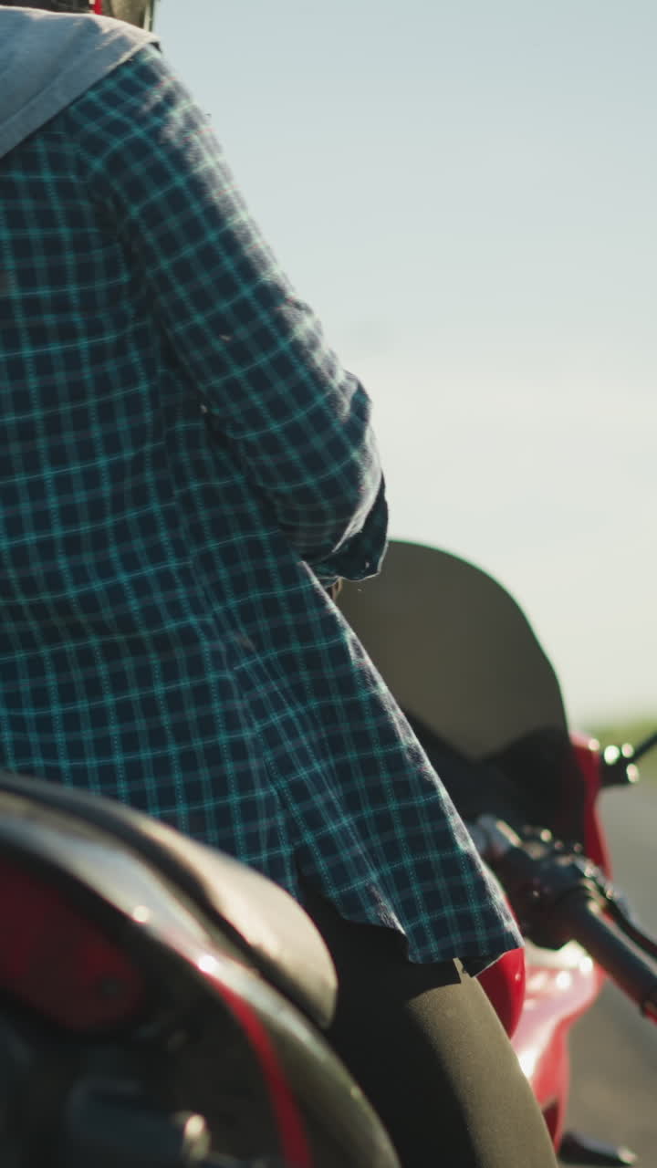 헬을 입은 여성 오토바이 운전자가 오토바이에 올라 타기 위해 준비하고 있으며, 배경은 울창한 초록색으로 흐릿합니다.