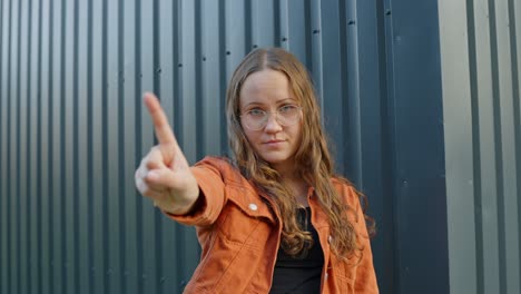 Woman-stares-down-shaking-finger-reminding-not-to-do-something-against-urban-crate-background