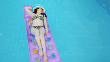 joven sexy tomando el sol en un colchón inflable, lujosa bajo el sol en la piscina