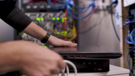 hombre configurando una computadora portátil y un cable lan en la sala de servidores