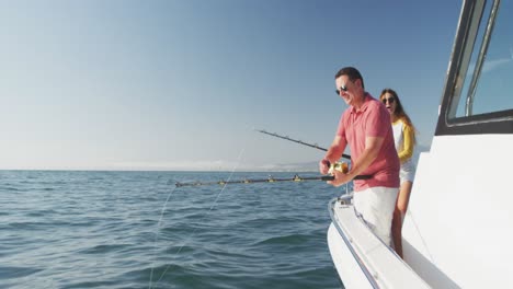 Side-view-of-a-Caucasian-man-and-his-teenage-daughter-fishing-on-boat-