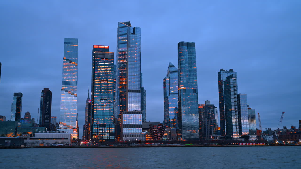 Nova York, EUA, 26 de março de 2026: Vista panorâmica dos arranha-céus de Hudson Yards na hora azul. Marcos arquitetônicos modernos e torres de escritórios iluminadas em Manhattan vistos do outro lado da água.